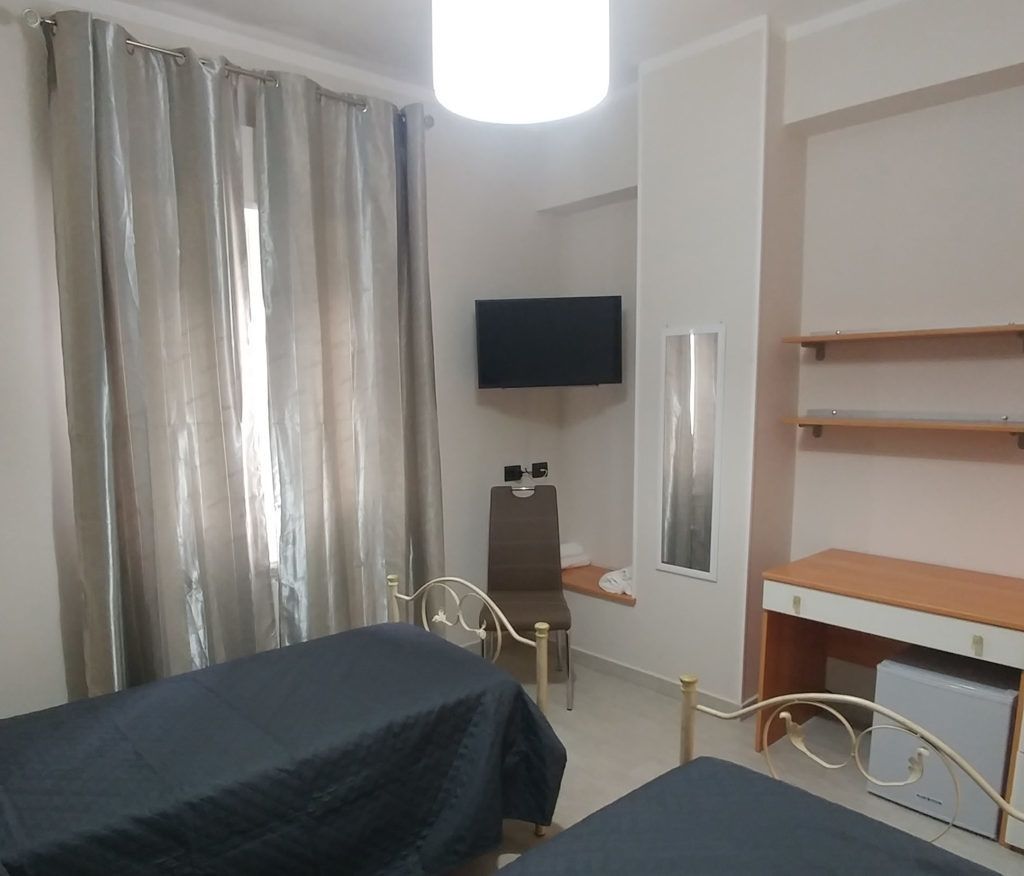 Habitación de hotel con dos camas, televisión, escritorio y silla.
