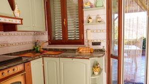 A kitchen with a stove, oven, and a window with blinds. - B&B Villa Bella (Catanzaro)
