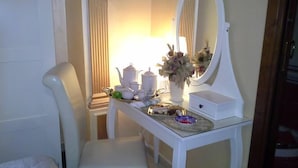 A hotel room with a white vanity, a chair, a table with tea set, and a mirror. - B&B Villa Bella (Catanzaro)