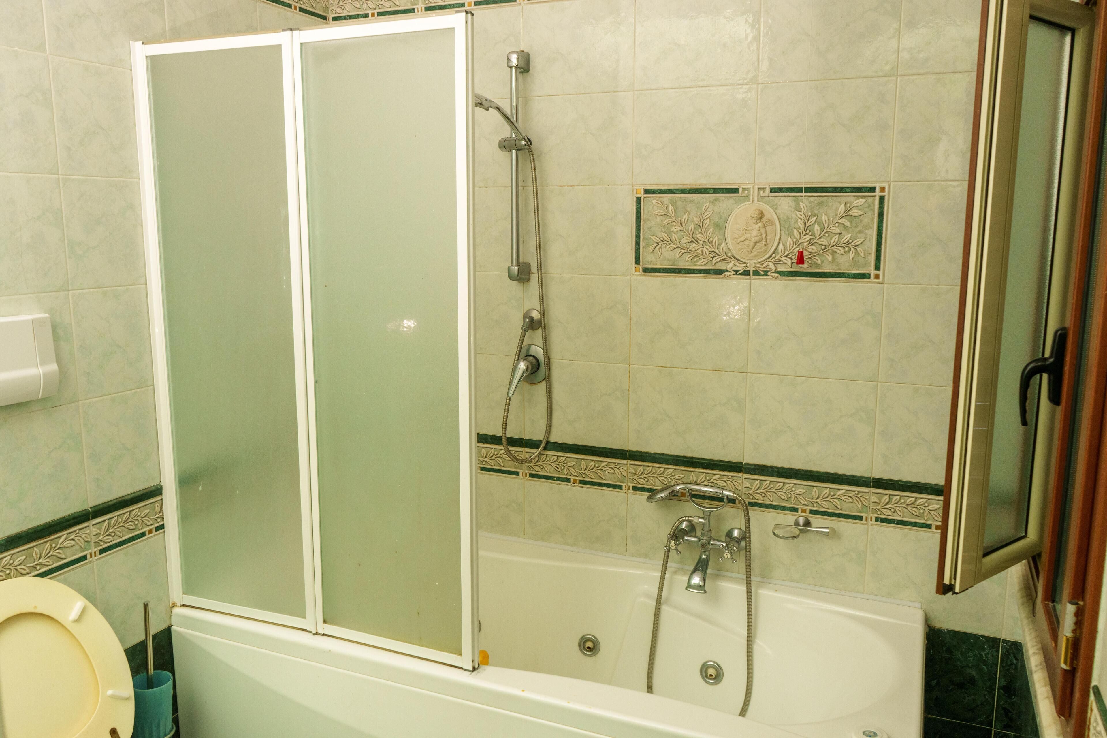 A bathroom with a glass-enclosed shower, a bathtub, and a toilet.