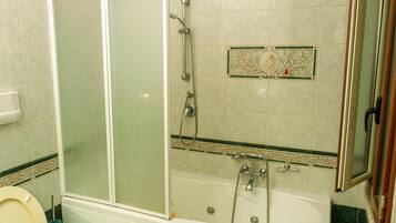 A bathroom with a glass-enclosed shower, a bathtub, and a toilet.