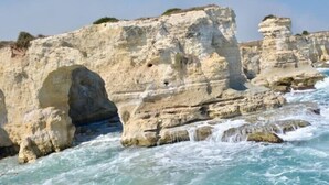 A coastal cliff with a large arch formation and waves crashing against the rocks. - Leonessa di Puglia (Altamura)