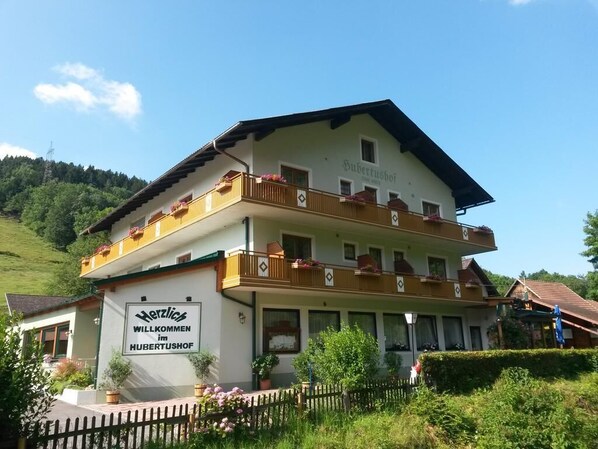 Un edificio de dos pisos con balcones y un cartel que dice "Herzlich Willkommen im Hubertushof".