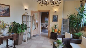 Ein geräumiger Raum mit Schreibtisch aus Holz, Korbmöbeln und Blumentöpfen.