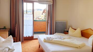 A hotel room with a bed, a desk, a chair, a radiator, and a view of the outside.