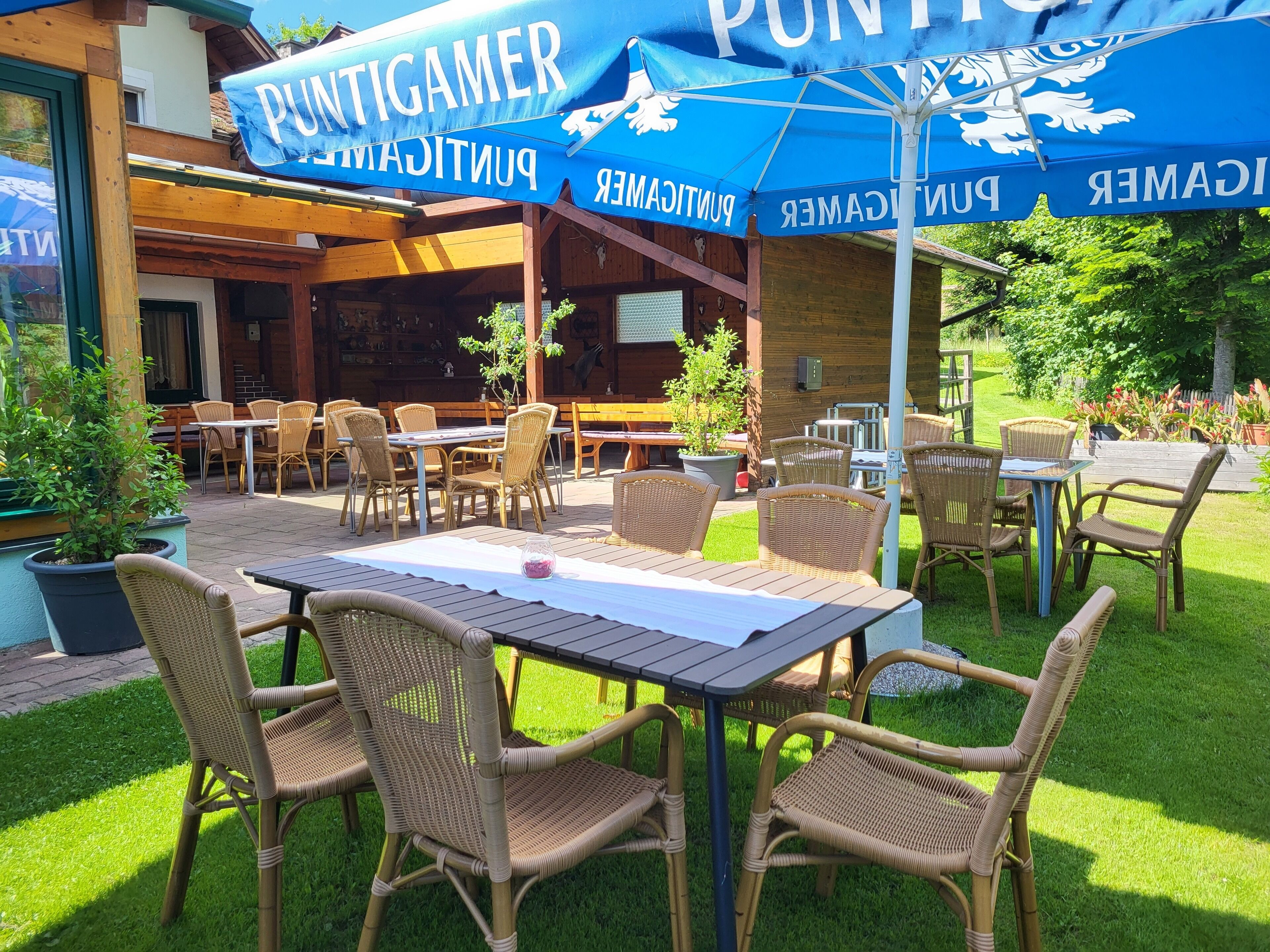 An outdoor seating area with wicker furniture and a blue umbrella with 'PUNTIGAMER' branding.