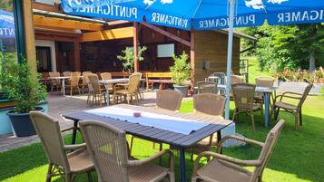 An outdoor seating area with wicker furniture and a blue umbrella with 'PUNTIGAMER' branding.