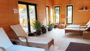 Eine Holzhütte mit zwei Liegestühlen, einem kleinen Tisch und Topfpflanzen.