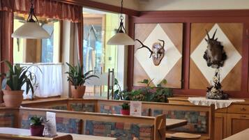 A restaurant interior with booths, hanging lamps, and decorative antler mounts on the wall.