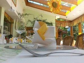 Mesa para comer con mantel blanco, copas transparentes y servilleta doblada.