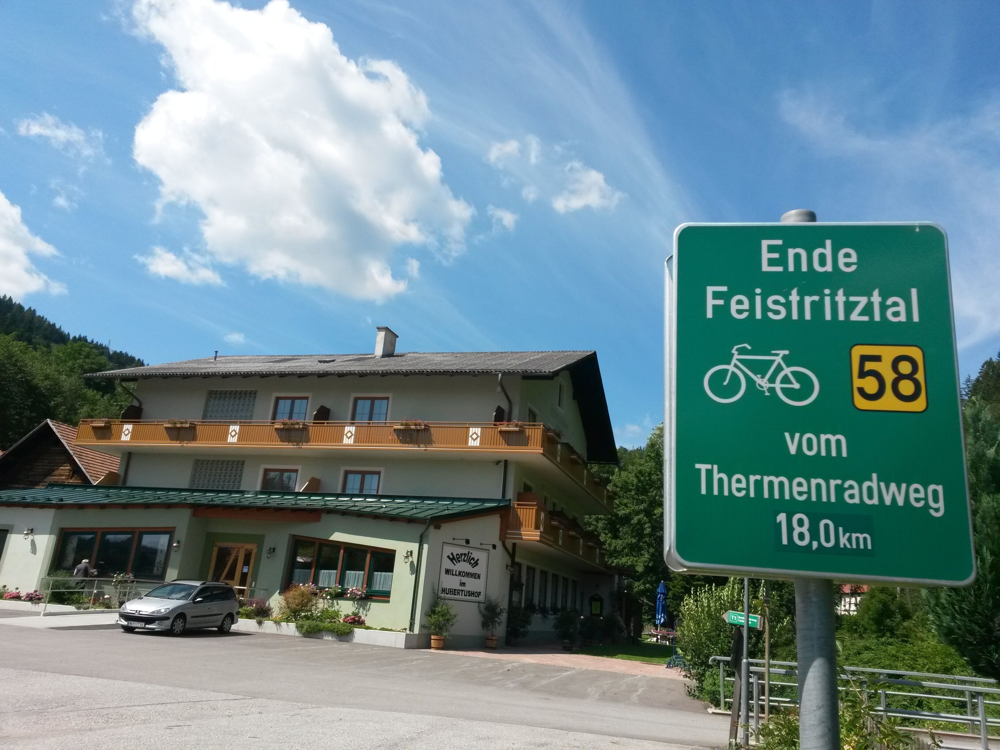A sign indicating the end of a cycling route, with a distance of 18.0 km from the previous point.