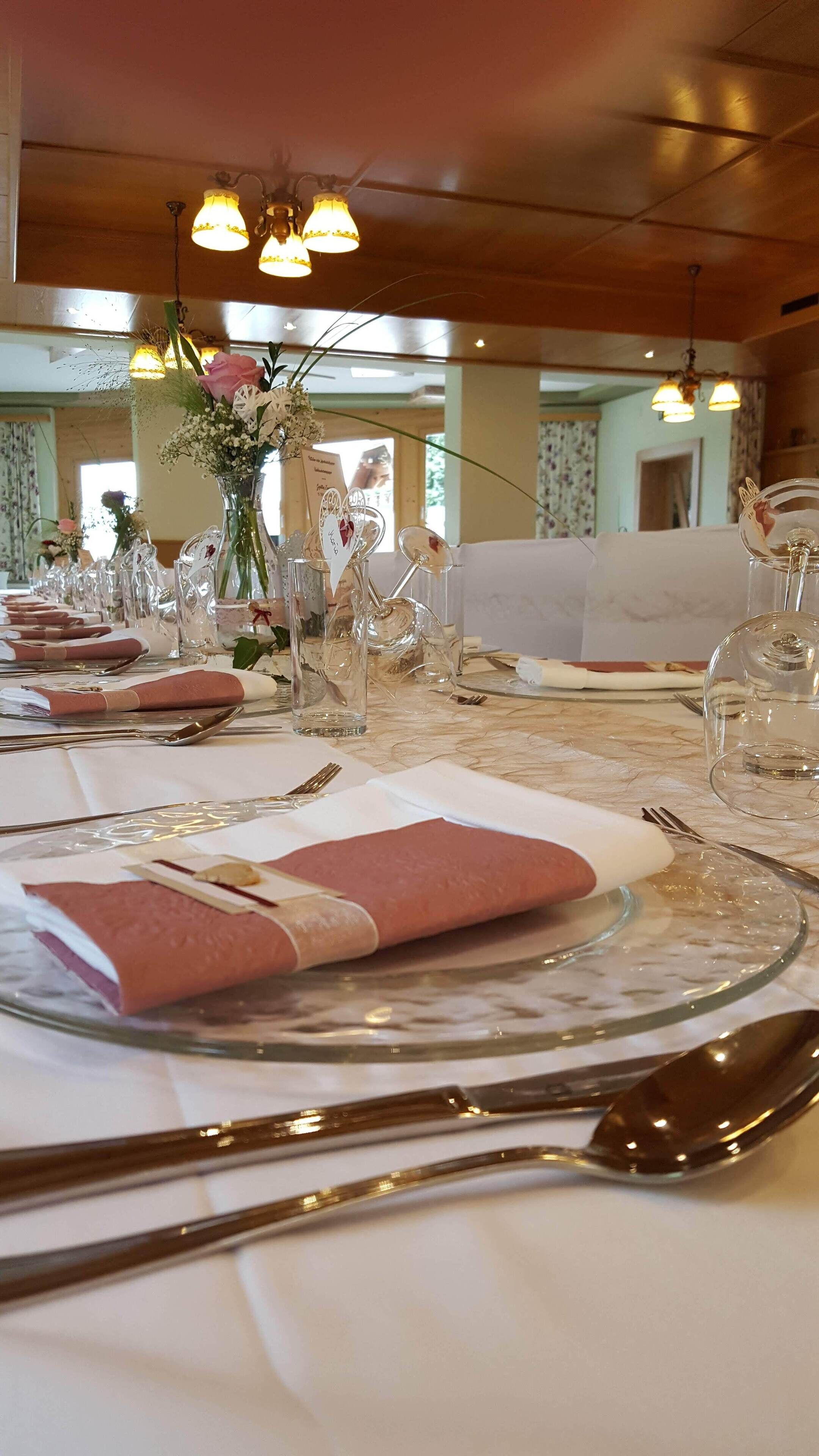 A dining table set with white tablecloths, clear glassware, and neatly folded napkins.