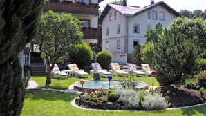 A hotel courtyard with a swimming pool, lounge chairs, and a well-maintained garden. - Hotel garni Schmideler (Sonthofen)