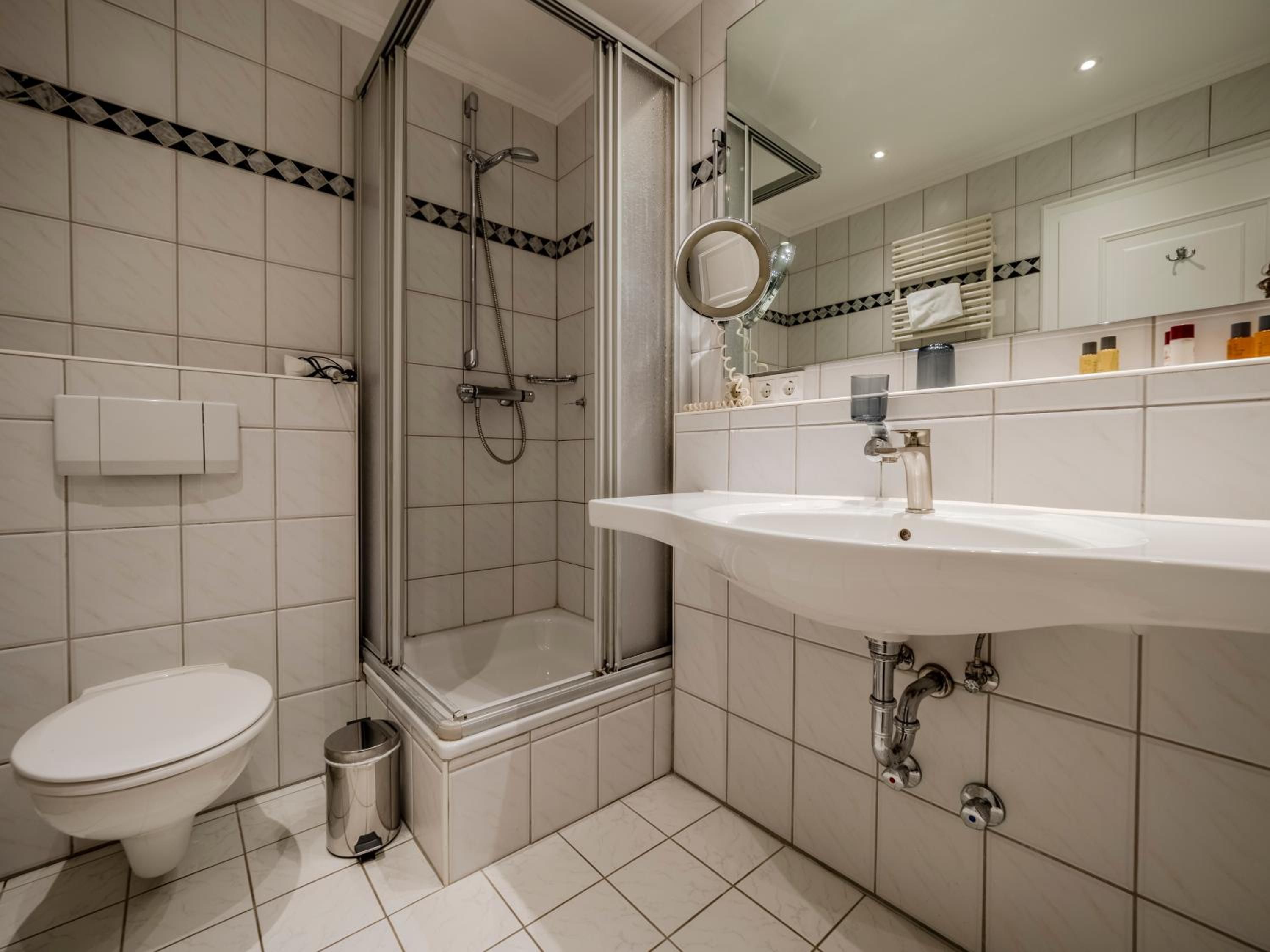 Ein modernes Badezimmer mit einer Duschkabine aus Glas, einem weißen Waschbecken und einer Toilette.