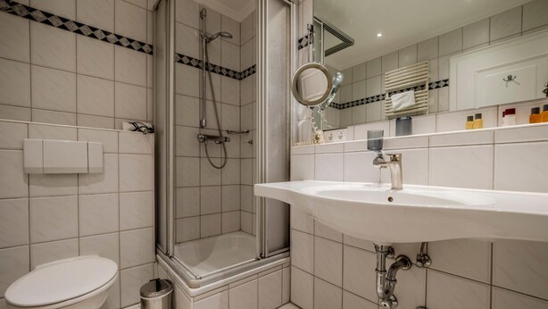 A modern bathroom with a glass-enclosed shower, a white sink, and a toilet.