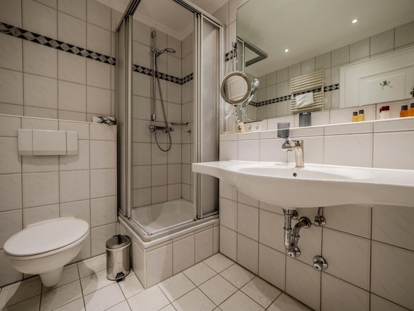 Une salle de bain moderne avec une douche à parois de verre, un lavabo blanc et des toilettes.