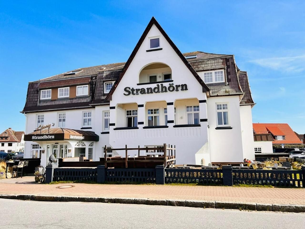 A white building with a black roof and the name 'Strandhorn' on the facade.