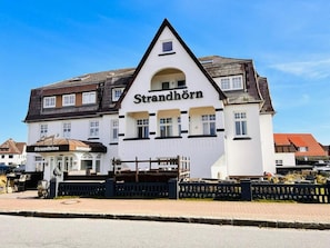 A white building with a black roof and the name 'Strandhorn' on the facade.
