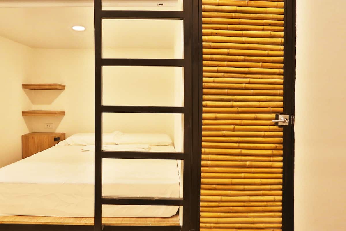 A room with a bed, a wooden nightstand, a wall-mounted shelf, and a sliding door with bamboo panels.