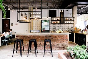A modern kitchen with a brick island, bar stools, and hanging pendant lights. - Santuario Getsemaní Hostel (Cartagena)