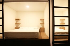 A single bed in a room with a wooden floor, white walls, and a small bedside table with a lamp. - Santuario Getsemaní Hostel (Cartagena)