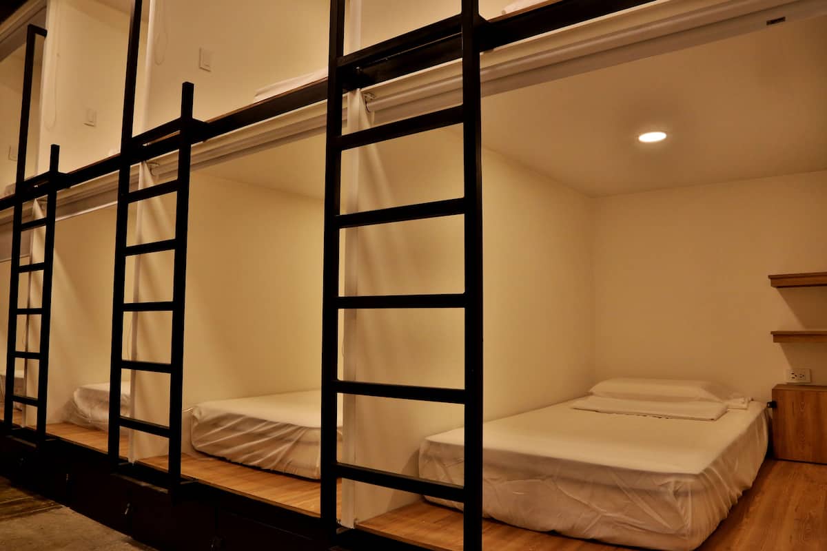 A bunk bed room with a ladder, a wooden nightstand, and a small shelf.