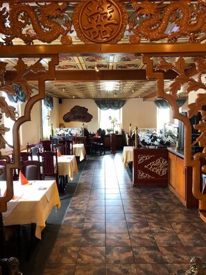 A restaurant interior with traditional decor, including wooden carvings and a tiled floor.
