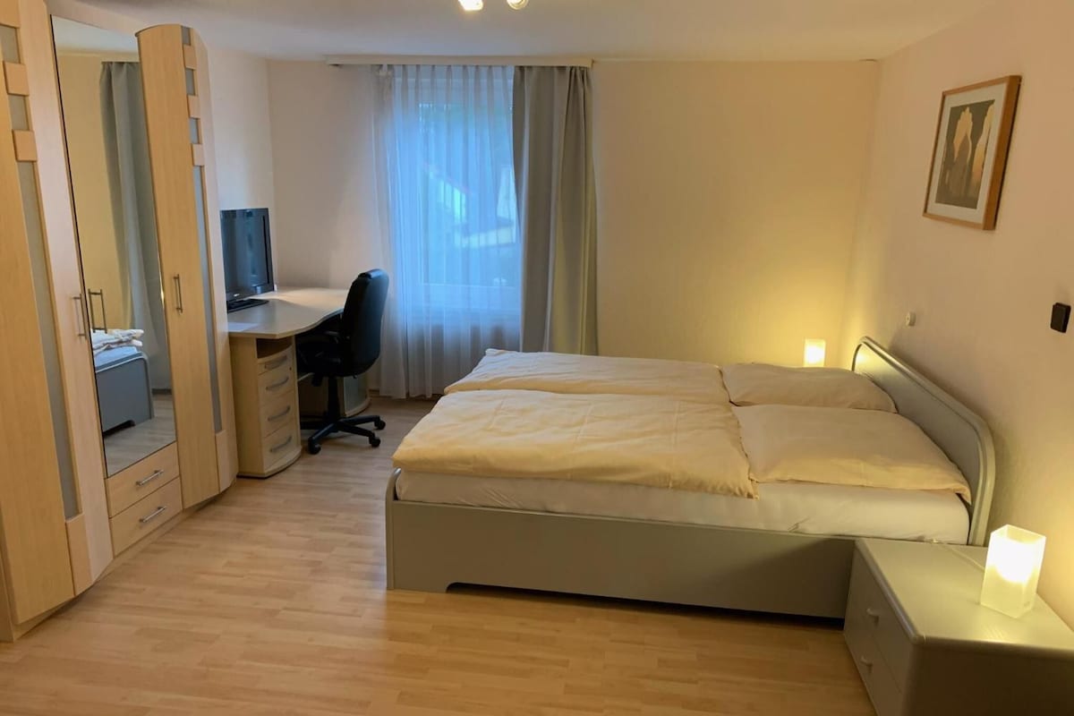 A bedroom with a bed, a desk, and a chair.