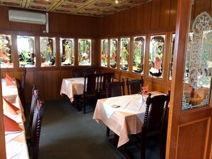 A restaurant interior with traditional Chinese window designs, wooden furniture, and a tiled floor.