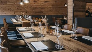 Een restaurant met houten wanden, meerdere tafels gedekt met wijnglazen en bestek, en hanglampen.