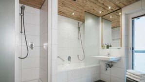Een moderne badkamer met een douche, bad en wastafel.