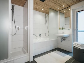 A modern bathroom with a shower, bathtub, and sink.