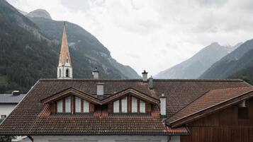 Un edificio con un tetto ripido, una torre imponente e montagne sullo sfondo.