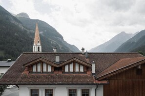 A building with a steeply pitched roof, a prominent tower, and a mountainous backdrop.