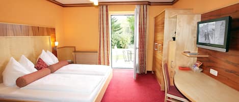 A hotel room with a bed, a desk, a television, and a view of the outdoors.