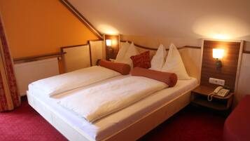 A hotel room with a double bed, two bedside tables with lamps, a red carpet, and a telephone on the right side.