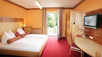 A hotel room with a bed, a desk, a television, and a view of the outdoors.