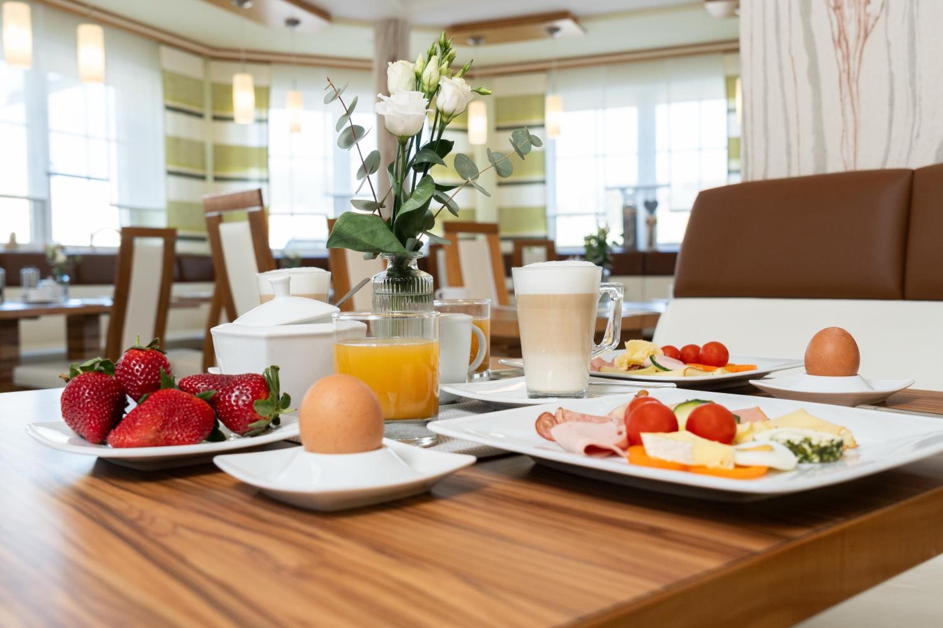 Ein Frühstückstisch mit Speisen, einer Blumenvase und einer Kaffeetasse.