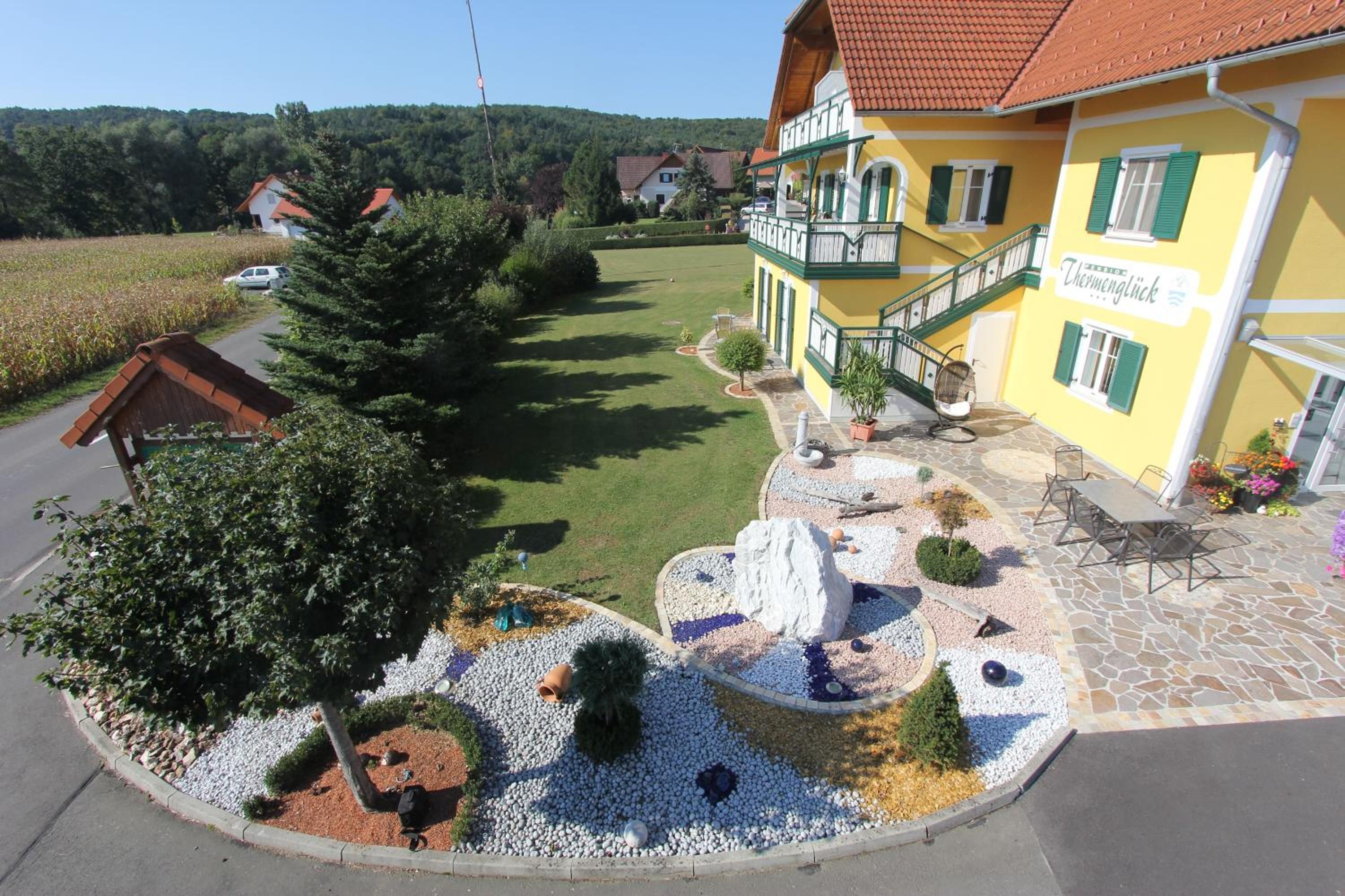 A yellow building with a green staircase and a stone patio with outdoor seating.