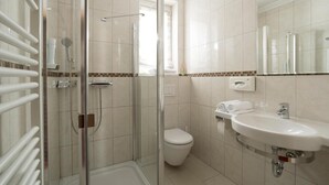 Une salle de bain avec une douche à parois de verre, des toilettes, un lavabo et un miroir.