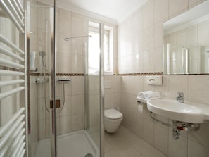 Un baño con cabina de ducha de vidrio, inodoro, lavabo y espejo.