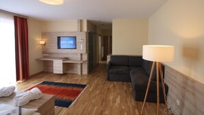 A modern hotel room with a TV, sofa, and a lamp. - Hotel Restaurant Schachenwald (Premstätten)