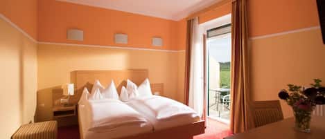 A hotel room with a bed, a desk, a chair, and a view of the outdoors.