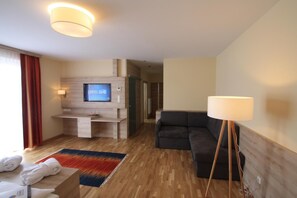 Una habitación de hotel moderna con televisor, sofá y lámpara.