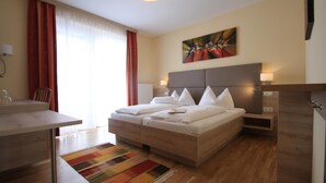 Une chambre d’hôtel moderne avec un grand lit, des tables de chevet, un bureau et un tapis aux couleurs vives.