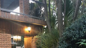 Un sendero de ladrillo que conduce a una zona techada con techo de madera y un aplique de pared.