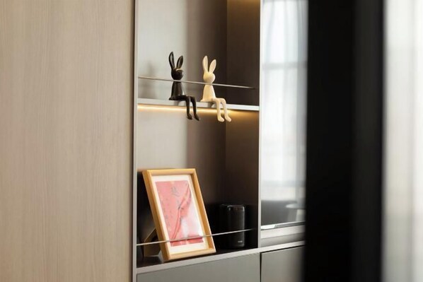 A modern interior with a minimalist design, featuring a shelf with two rabbit figurines and a framed picture. - Zhouji Hotel (Zhoushan)