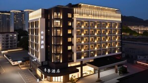 Un hôtel moderne, doté de plusieurs étages, de grandes fenêtres et d’une façade bien éclairée.