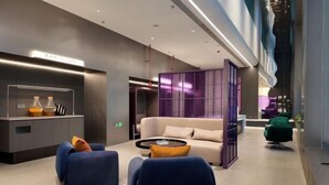 Un hall d’entrée moderne avec un canapé, des fauteuils, une table basse et un comptoir d’accueil.