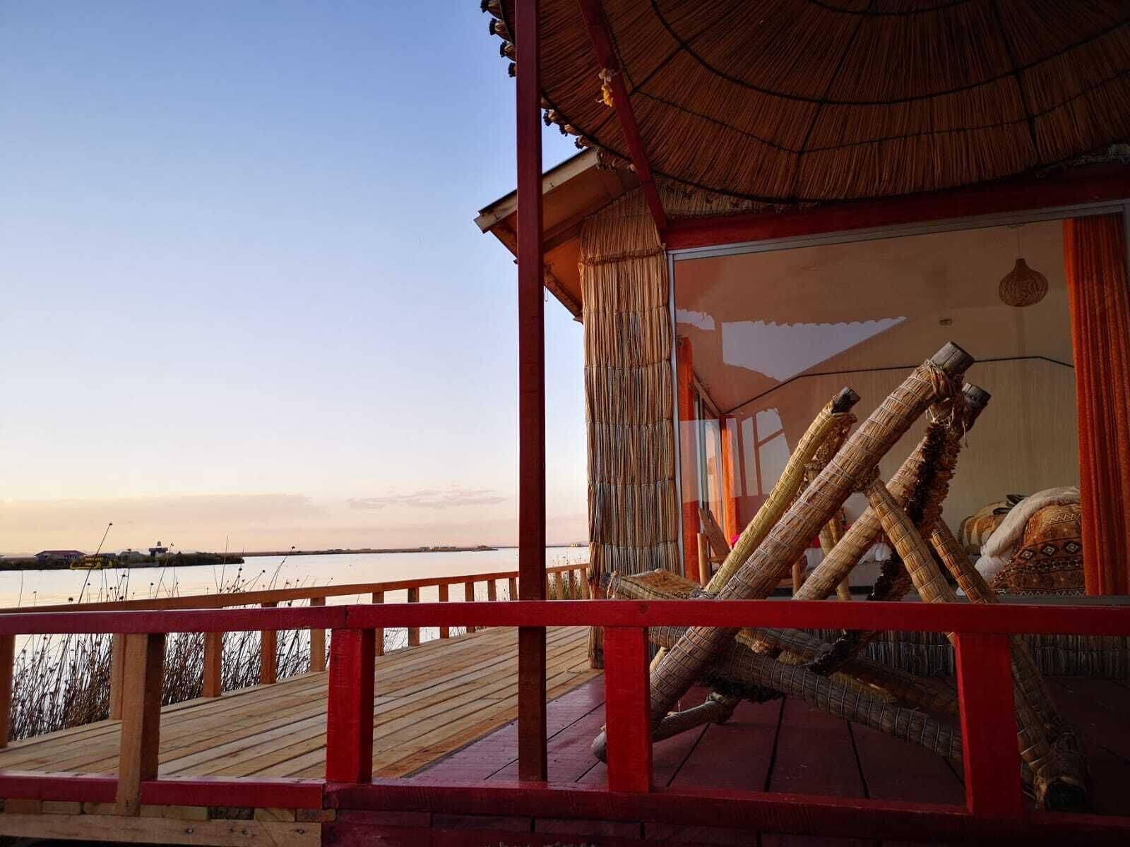 A wooden deck with a red railing, overlooking a body of water.